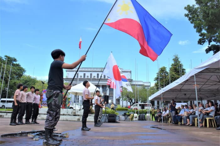 西ネグロス州庁舎前で比日韓米の国旗を掲げる地元少年劇団の劇団員たち