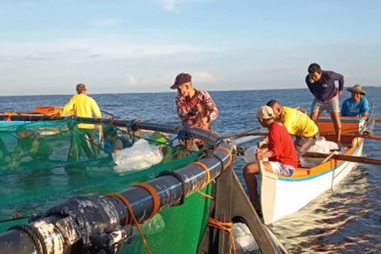 養殖ケージで作業する漁師ら（資料写真）