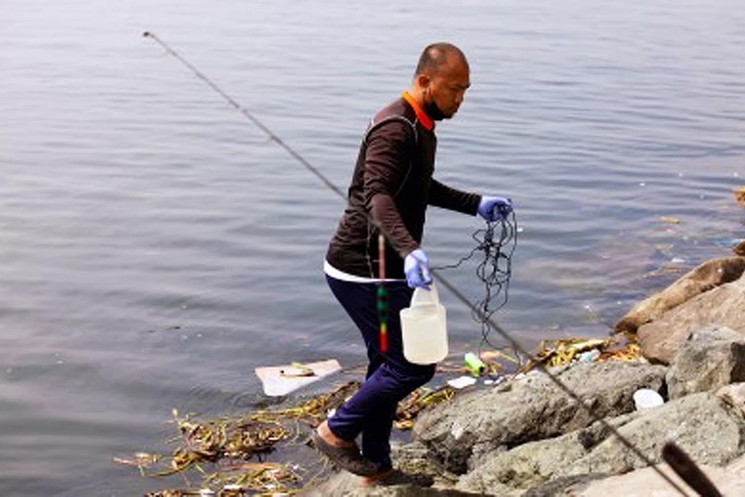 ロハス大通り沿いのマニラ湾で水質サンプリングとモニタリングを実施する環境天然資源省職員