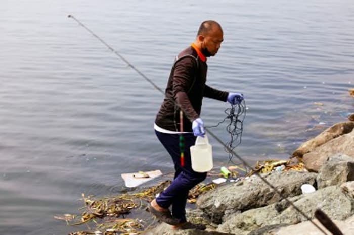 ロハス大通り沿いのマニラ湾で水質サンプリングとモニタリングを実施する環境天然資源省職員