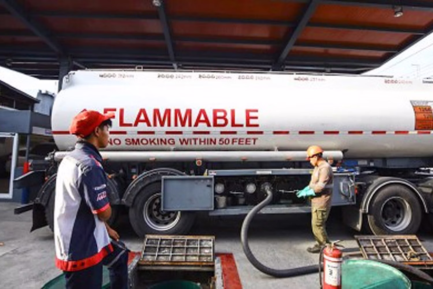 タンクローリーからガソリンスタンドの地下タンクに燃料を補給する作業員（資料写真）