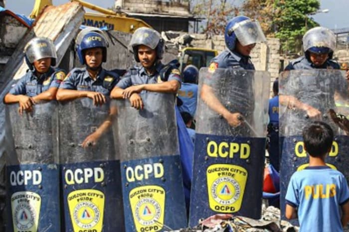 違法占拠住民居住区で発生した火災の片付け作業を警備する首都圏警察ケソン署の警官ら