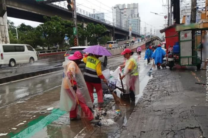 道路の排水溝付近にたまったごみを取り除くMMDA職員ら