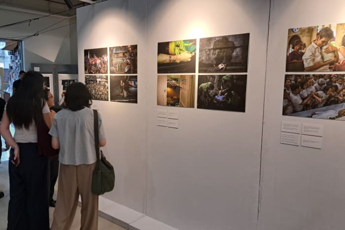 麻薬戦争の実態を伝える写真展を見る若い学生らに自身の家族の被害を伝える遺族(右から2人目奧の女性)