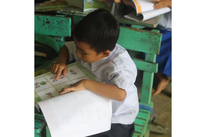 イロイロ州政府から提供された読み取り教材を使う小学校低学年の生徒たち