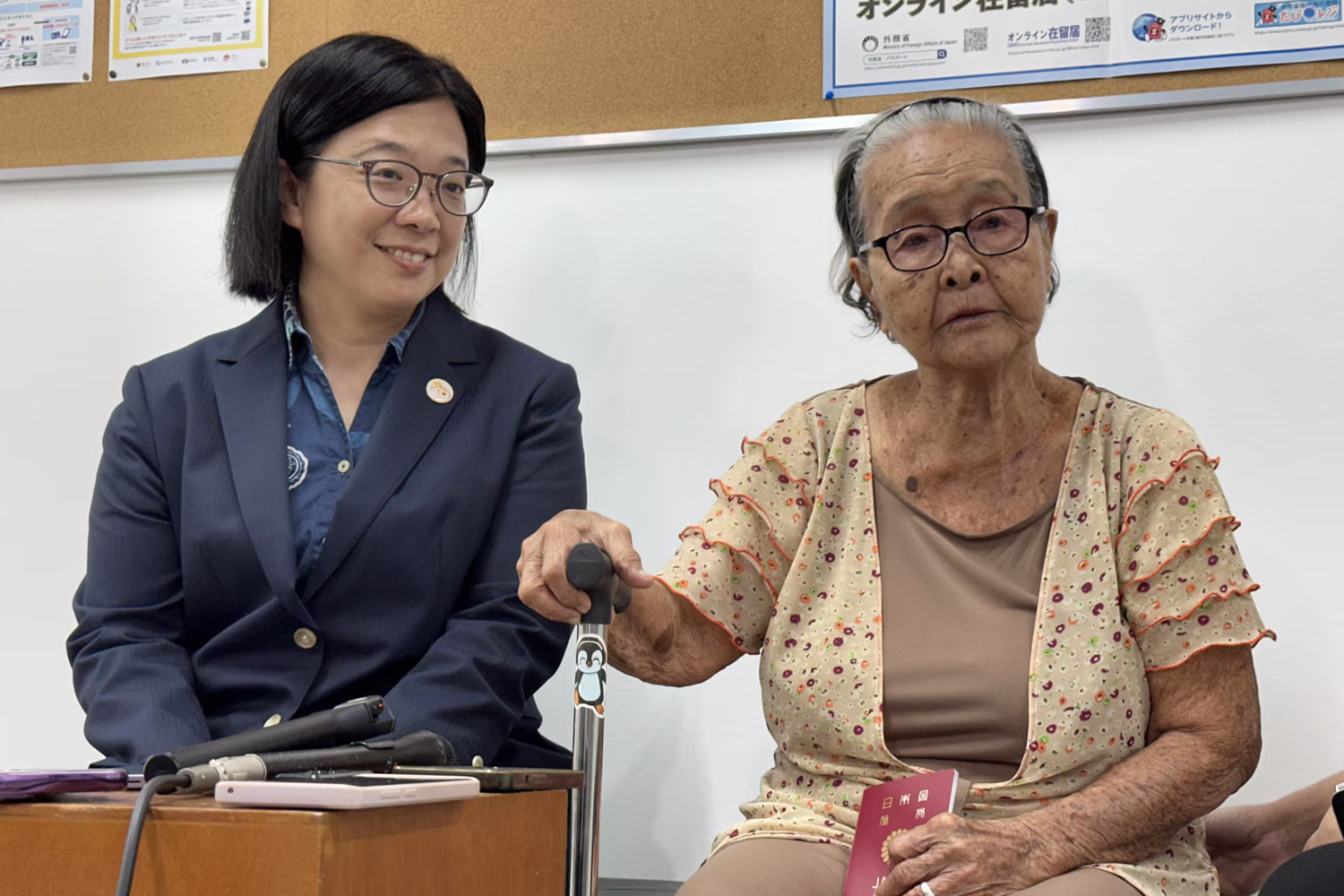 日本旅券を受け取った賀数アデライダさん（右）。